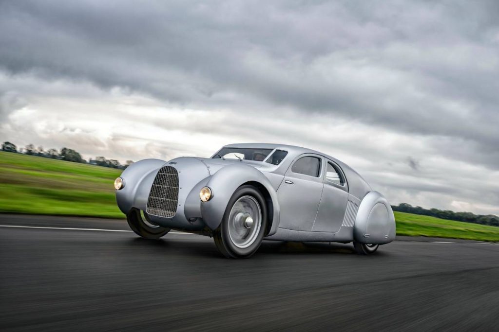 Cabriolife also presents classic car events: the Auto Union Type 52 - also known as the "Silver Arrow" - drives through a green landscape on gray asphalt. The sky is overcast.