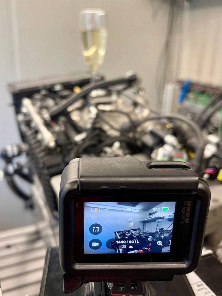 Das Bild zeigt den sogenannten Champagner-Motor von Obrist, auf dem ein Glas Champagner steht.