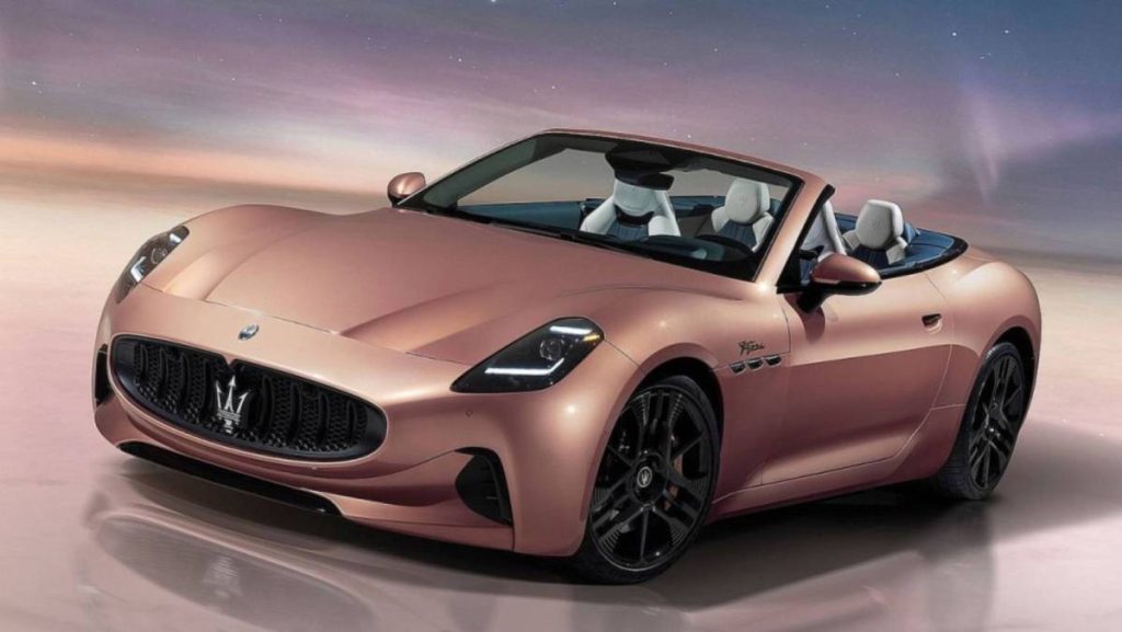 Man sieht eine Studioaufnahme des Maserati GranCabrio Folgore in einer ganz besonderen Farbe: Rosa-Braun-Metallic. Die Ledersitze sind schwarz-weiß. Am Kühler ist groß das Logo von Maserati zu sehen.