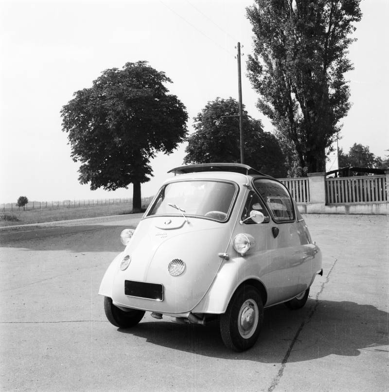 A black and white picture of a white Isetta convertible with the roof slightly open.