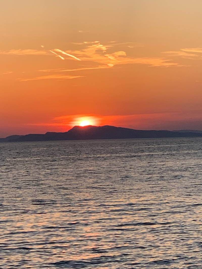 Cabriolife on Tour: Spektakulärer Sonnenuntergang am Meer direkt über der Insel Pag. Im Vordergrund glitzert die Adria mit zahllosen kleinen silbernen Wellen.