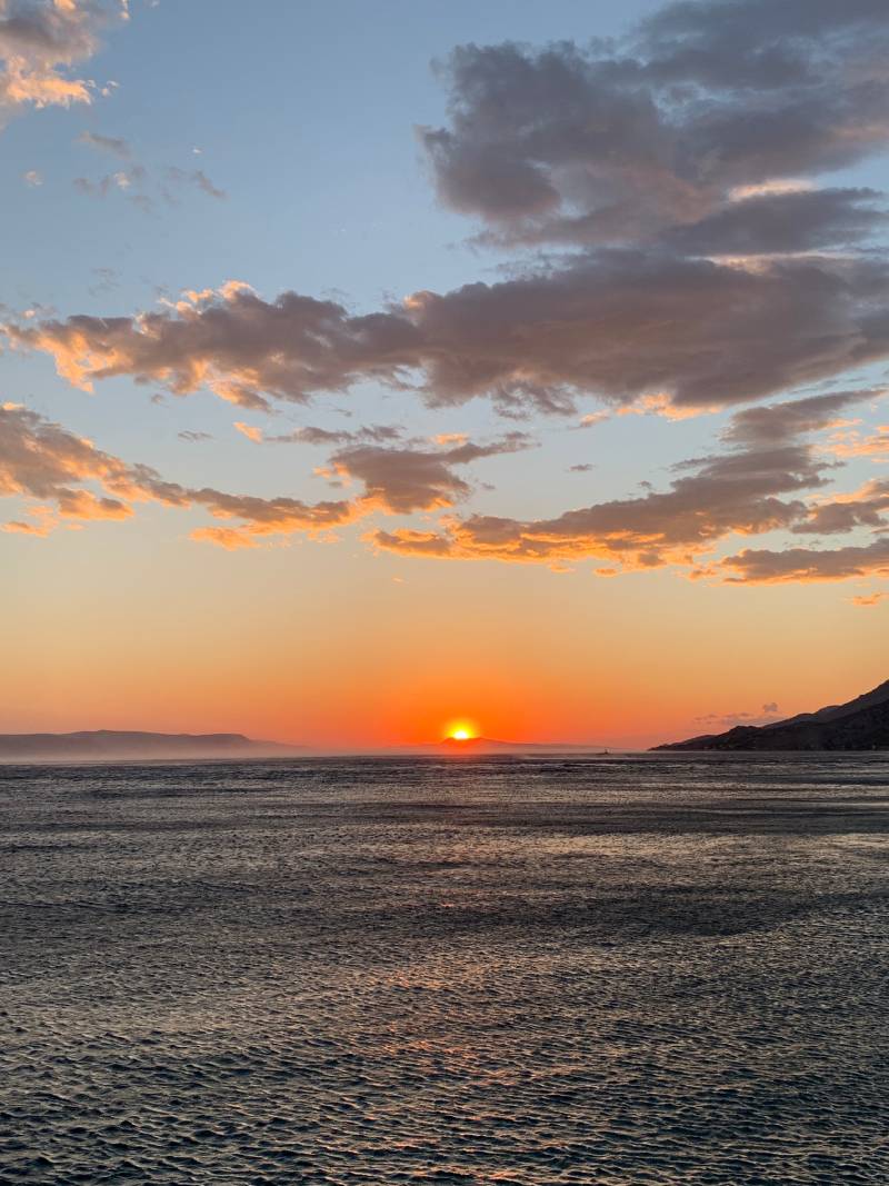 Cabriolife on Tour: Dramatischer Sonnenuntergang an der Küste Dalmatiens mit eindrucksvollen Wolken am Himmel. Das Wasser der Adria kräuselt sich in zahllosen kleinen Wellen.
