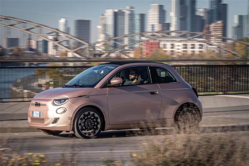 Ein junger Mann mit Bart fährt im FIAT 500e Cabrio mit geschlossenem Verdeck durch die Stadt.