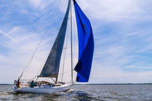 Omega 42 vom schwedischen Yacht-Designer Peter Norlin gilt als Ikone des Bootsbaus – vergleichbar mit dem Status eines Jaguar E-Type oder Mercedes SL Roadster. Auf dem Bild mit blauem Himmel und ein paar Schleierwolken segelt das Boot unter royalblauem Gennaker.