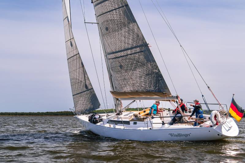 Omega 42 vom schwedischen Yacht-Designer Peter Norlin gilt als Ikone des Bootsbaus – vergleichbar mit dem Status eines Jaguar E-Type oder Mercedes SL Roadster. Auf dem Bild mit stahlblauem Himmel sieht man das Boot und die Crew voll am Wind.